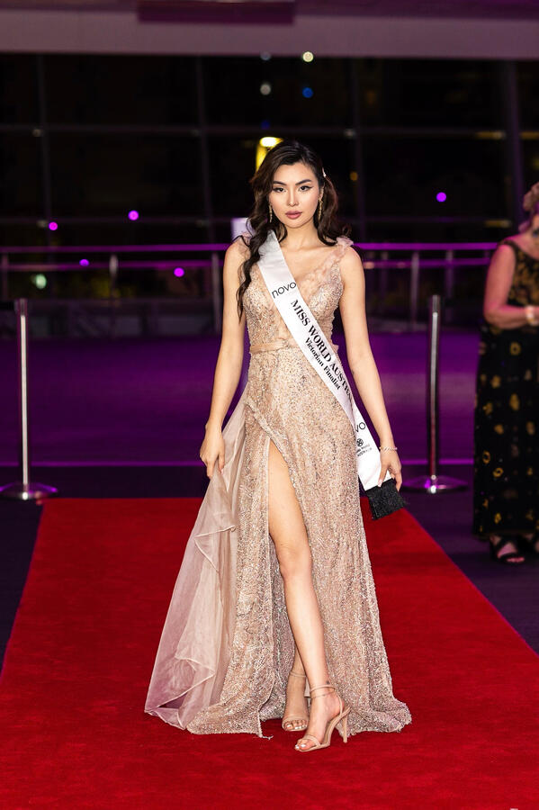 Lenny Cheng posing on the red carpet in a champagne gown during the Miss World Australia Queensland event.
